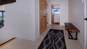 A hallway with a wooden door, a bench, and a patterned rug. - The Outlook, New 2BD/2.5BA home w/garage, VIEWS! (Mt. Crested Butte)