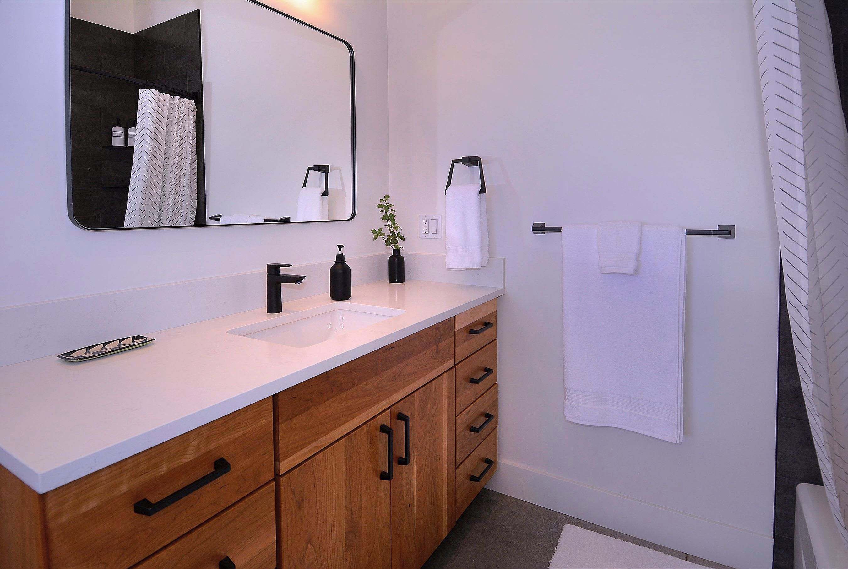 Une salle de bain moderne avec un lavabo blanc, un meuble-lavabo en bois et un grand miroir.