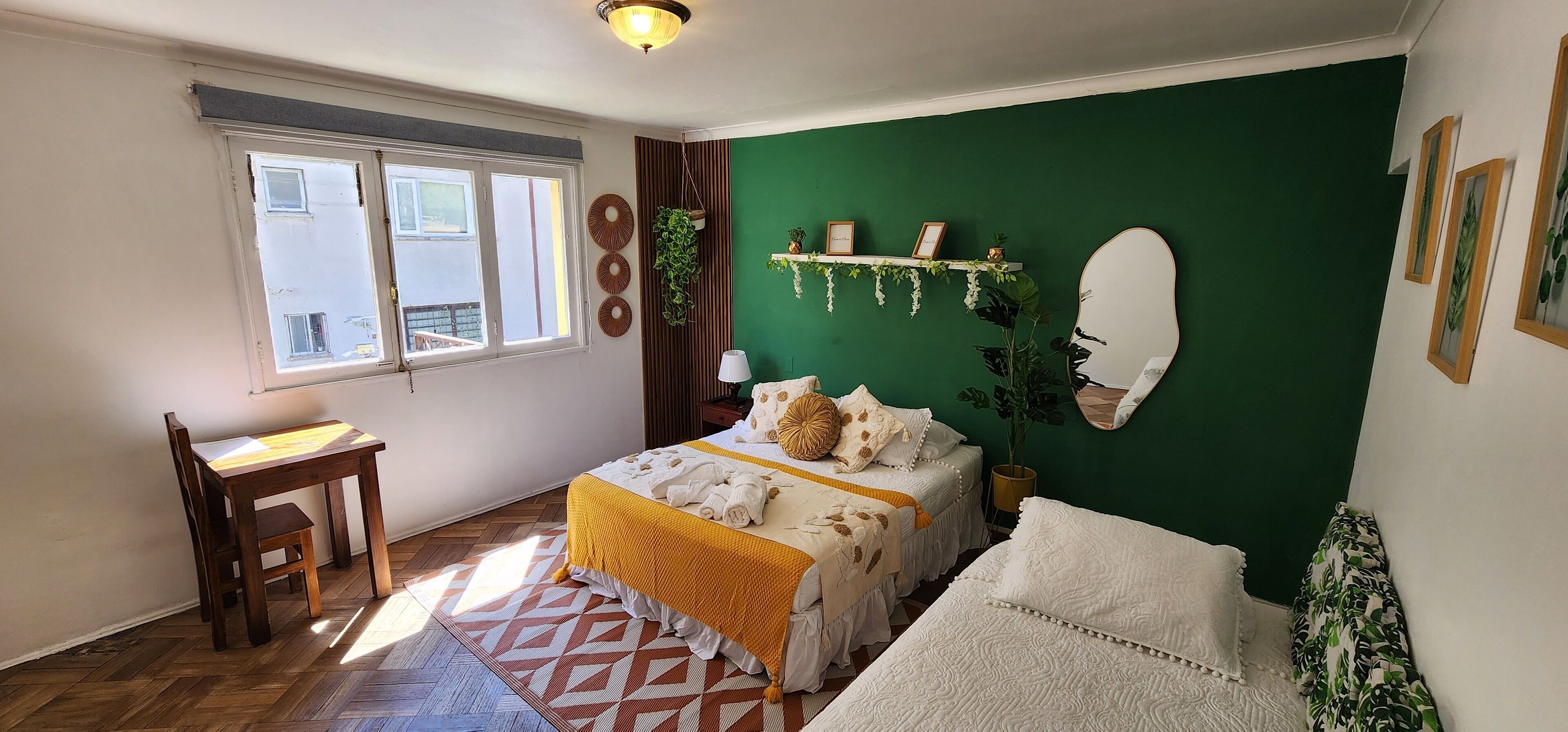 Une chambre à coucher avec un lit, un bureau, une chaise, un mur vert et une fenêtre.