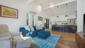 A modern living room with a blue sofa, a white armchair, and a patterned rug.