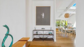 A modern dining area with a wooden bench, a dining table, and a wall-mounted abstract art piece.