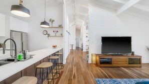 Une cuisine moderne avec un coin bar, un plancher en bois et un grand téléviseur à écran plat.