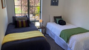 Une chambre avec deux lits, une fenêtre et une petite table avec une lampe.