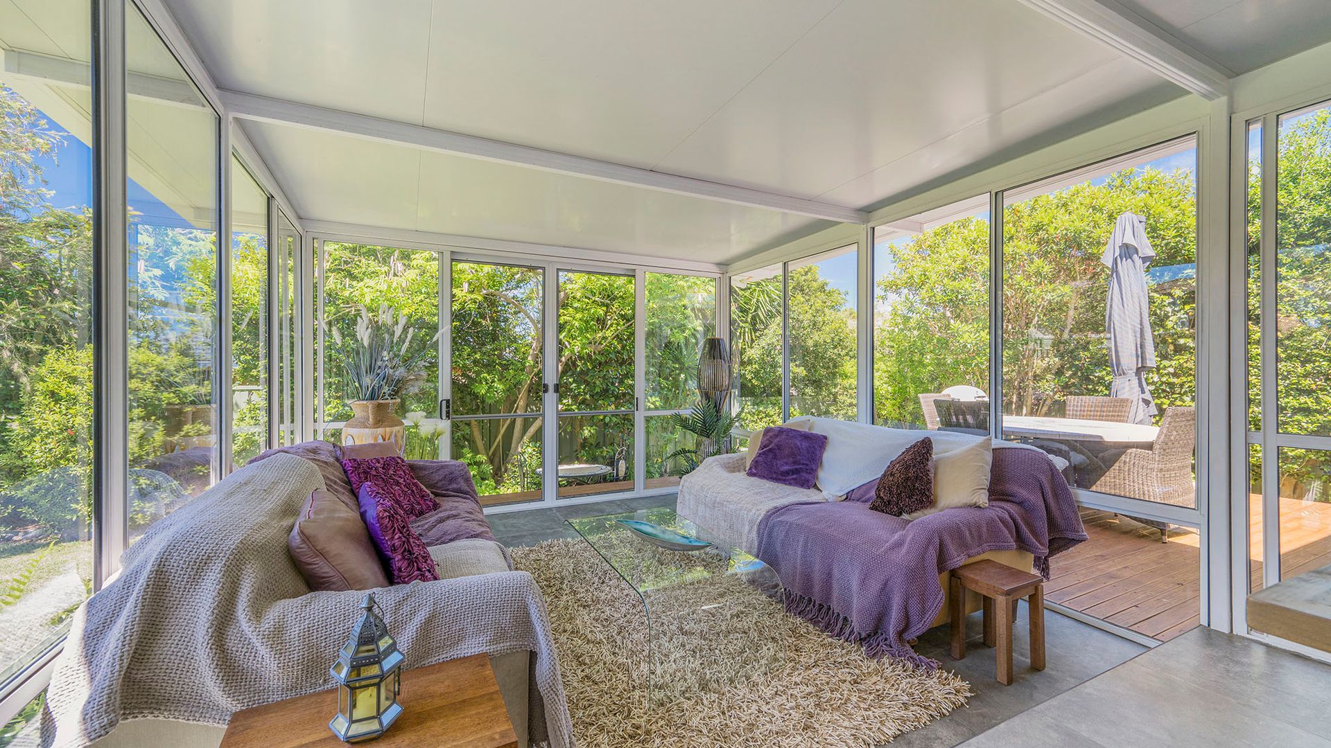 Un interior moderno con techo de vidrio, un conjunto de sofás y una zona de comedor con vistas al exterior.