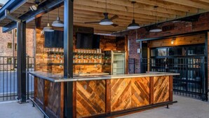 A bar area with a wooden counter, hanging pendant lights, and a brick wall backdrop. - BRAND NEW! Vibrant & Exquisite -1 Mile to Downtown (Nashville)