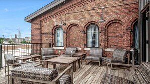 A brick building with a balcony featuring wicker furniture and a wooden deck. - BRAND NEW! Vibrant & Exquisite -1 Mile to Downtown (Nashville)