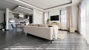 Un salon moderne avec un canapé, un coin repas et une cuisine en arrière-plan.