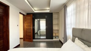 Une chambre à coucher avec un lit, une armoire, un miroir et une fenêtre avec des rideaux.
