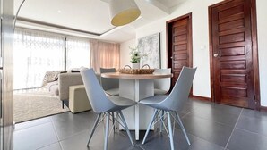 Un espace repas moderne avec une table ronde, deux chaises grises et un luminaire suspendu.