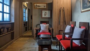 Habitación de hotel con cama, dos sillas, una mesita, un espejo y cuadros en las paredes.