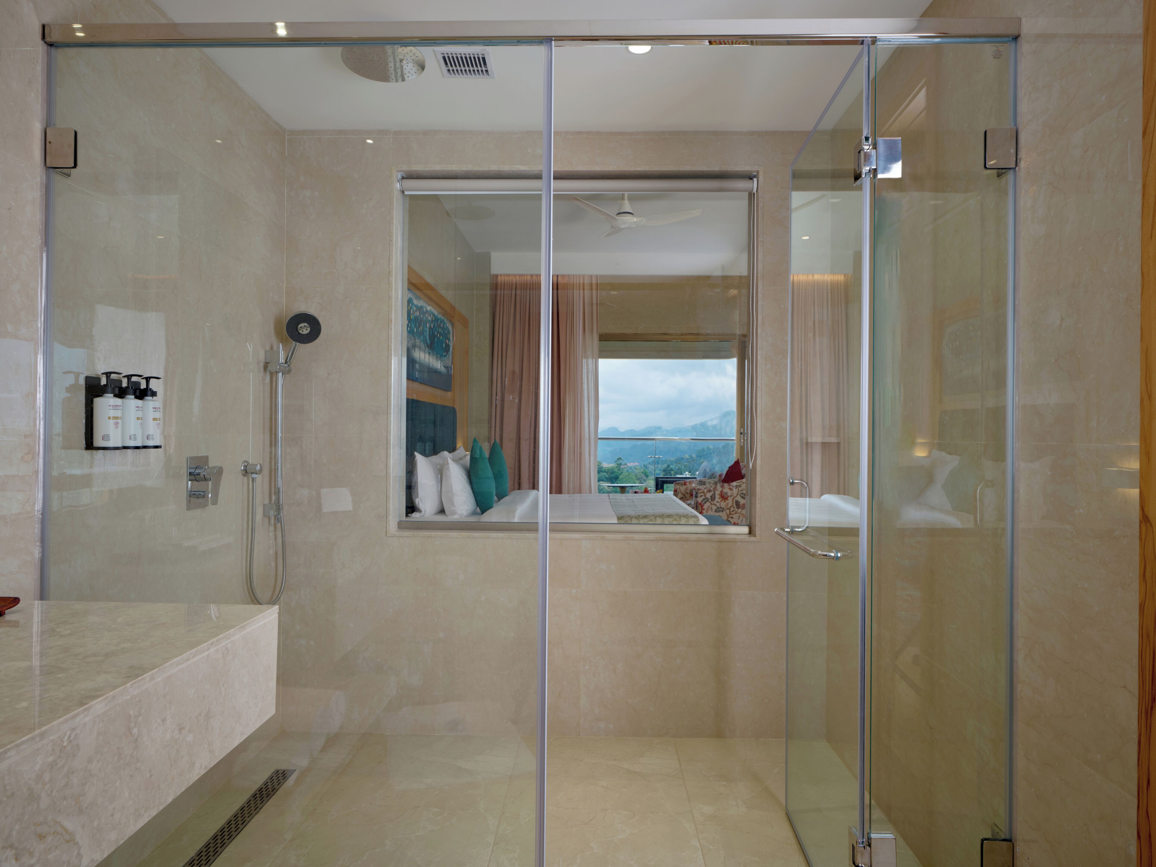A modern bathroom with a glass shower enclosure, a sink, and a window with a view.