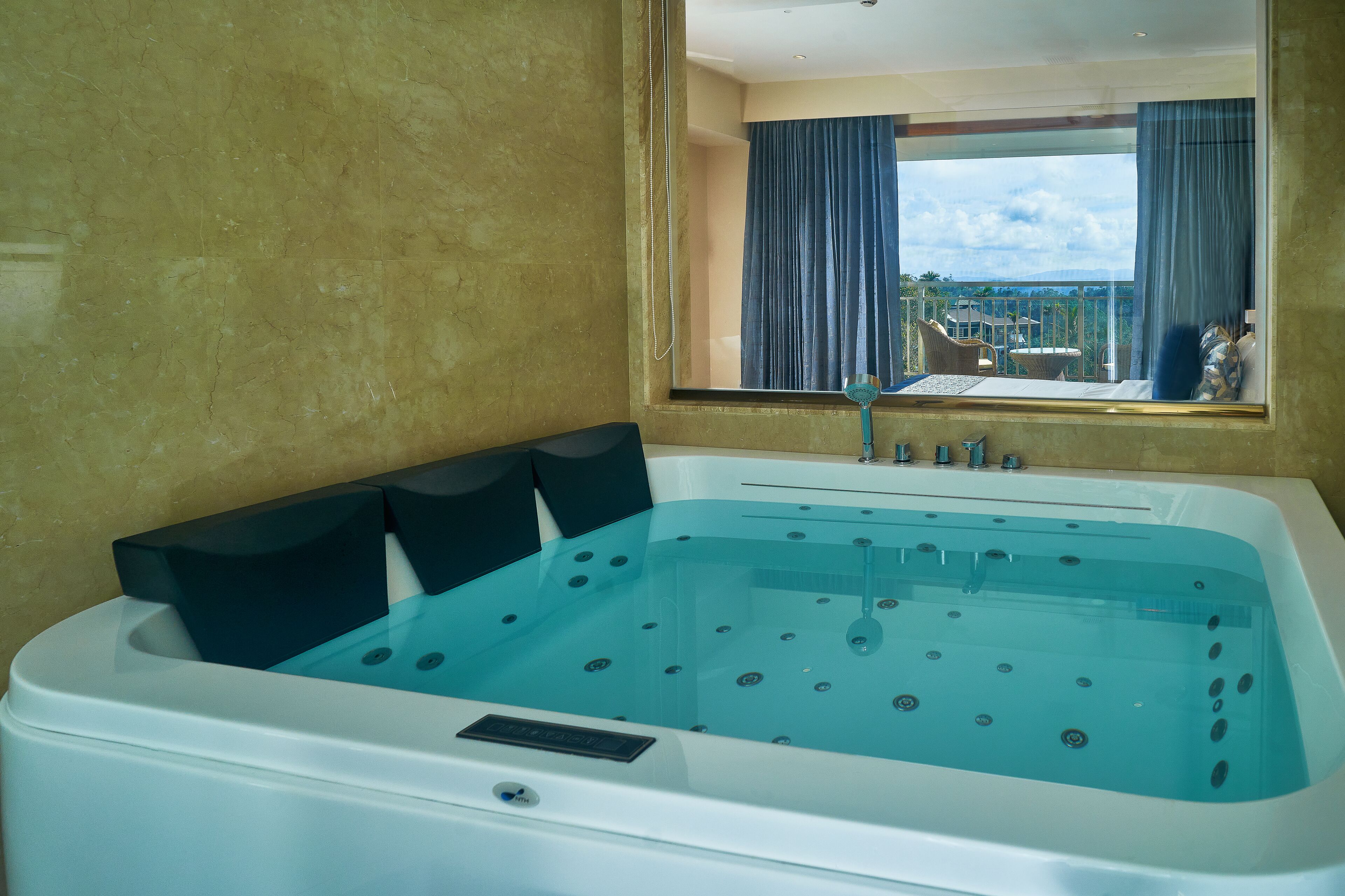 A large, clear hot tub with a view of a balcony and mountains in the background.