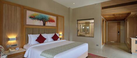 A modern hotel room with a large bed, a ceiling fan, a painting on the wall, and a bathroom mirror.