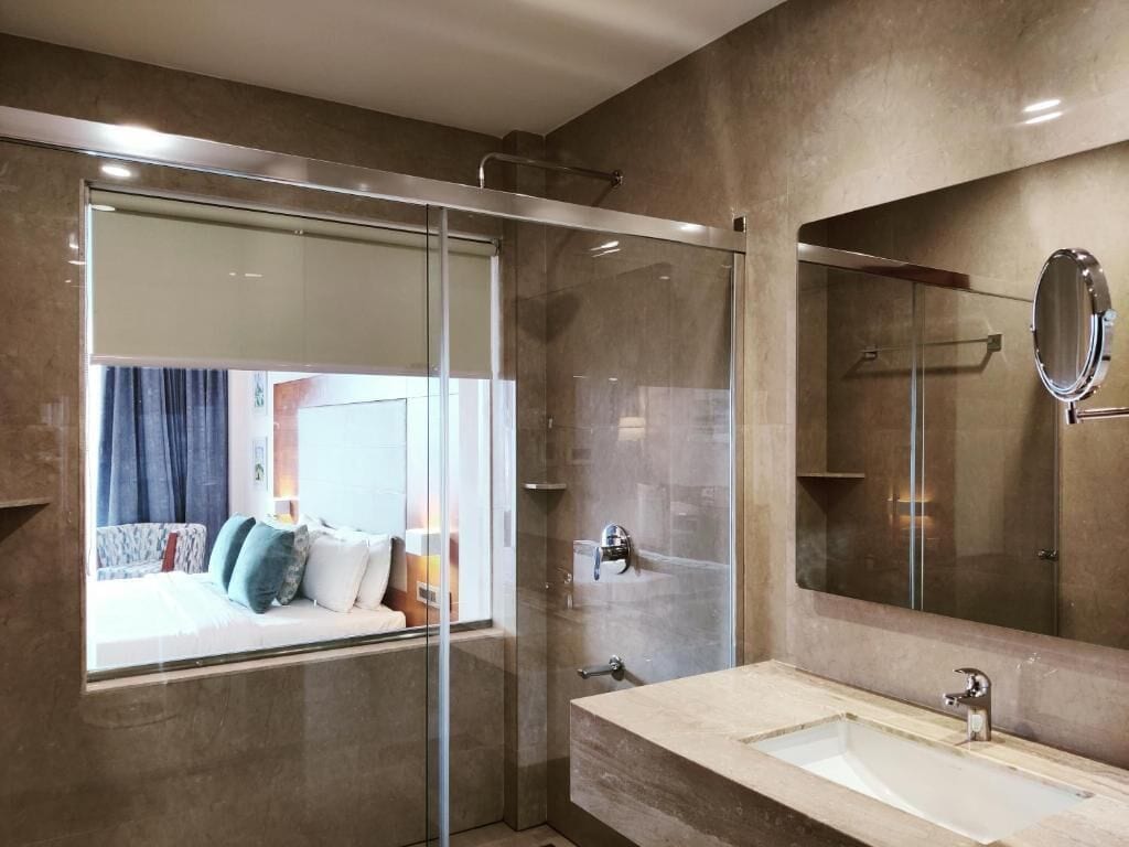 Un baño moderno con cabina de ducha de vidrio, un espejo grande y un lavamanos color beige.