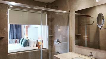 Un baño moderno con cabina de ducha de vidrio, un espejo grande y un lavamanos color beige.