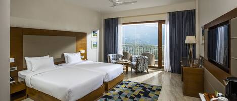 A hotel room with two beds, a balcony, a TV, and a coffee maker.