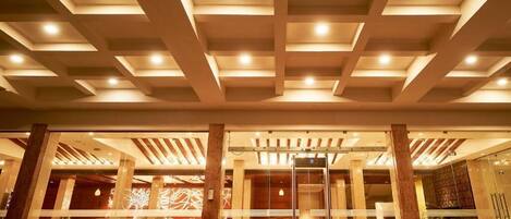 A hotel lobby with a red carpet, seating area, and a glass entrance.