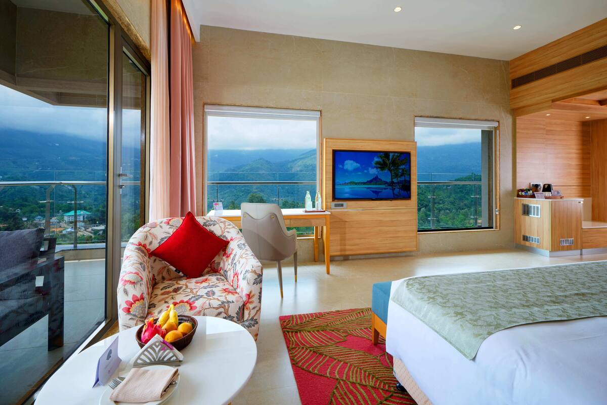 Ein Hotelzimmer mit Bett, Sofa, Fernseher, Schreibtisch und einem Balkon mit Blick.