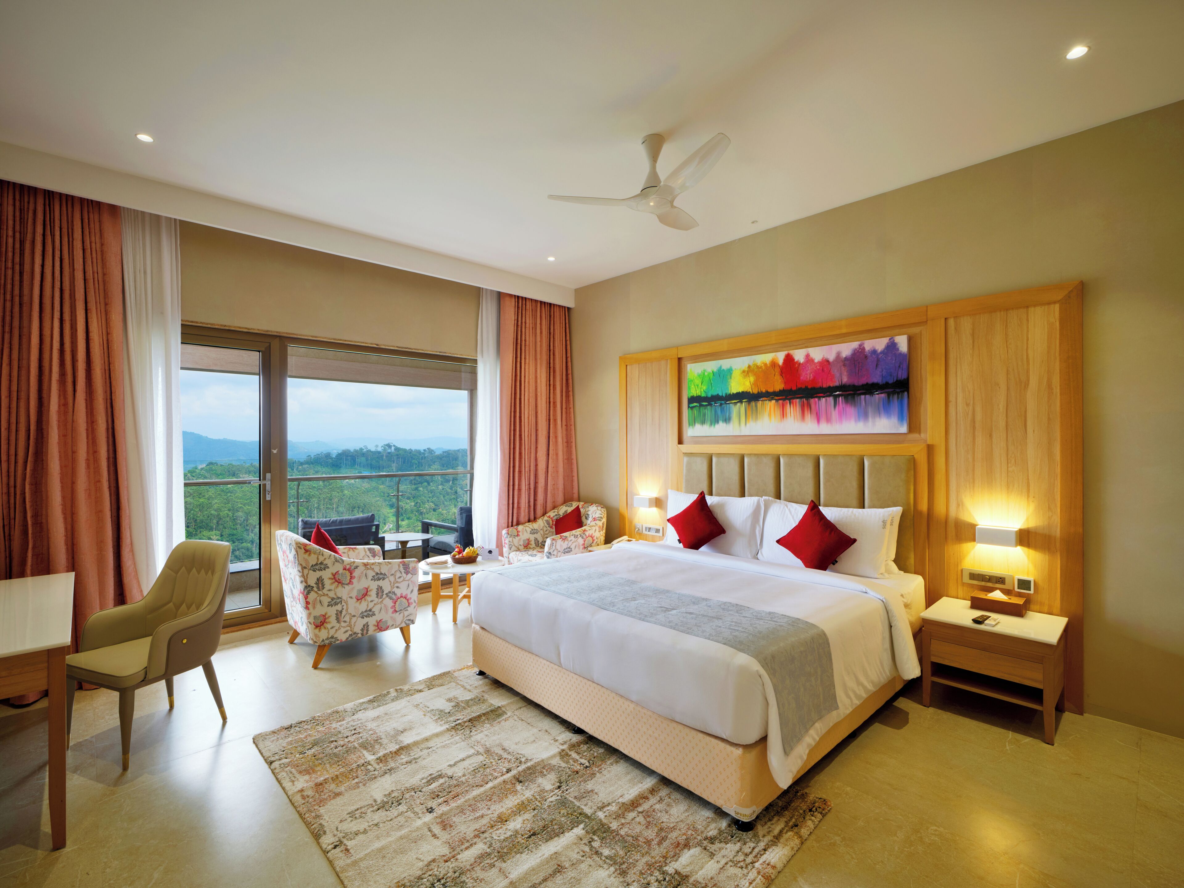 A hotel room with a large bed, a ceiling fan, a view of the outdoors, and a painting on the wall.