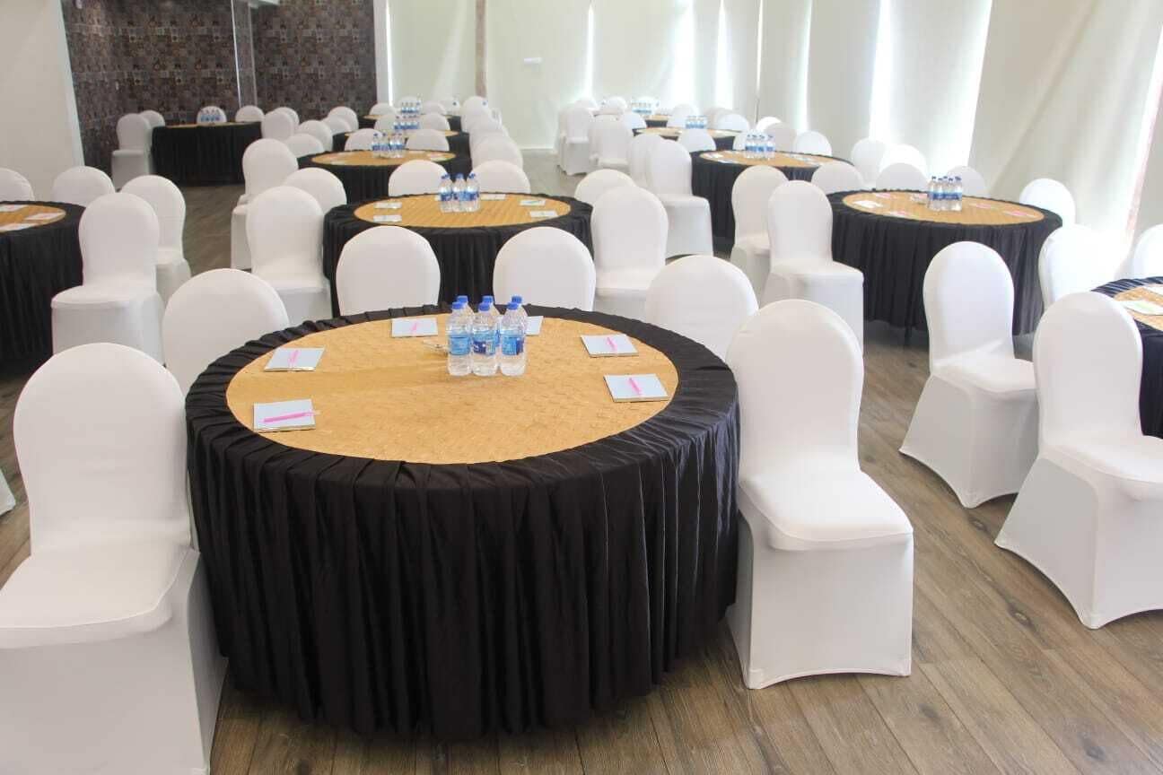 A conference room with round tables, white chairs, and black tablecloths.