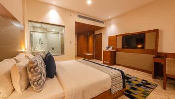 Une chambre d’hôtel avec un grand lit, un bureau, un miroir et un espace douche.