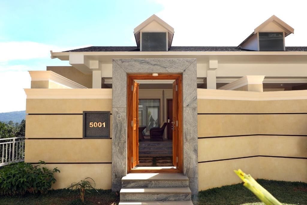 A modern building with a beige facade, a stone entrance, and a number '5001' on the wall.