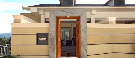 Un edificio moderno con fachada color beige, entrada de piedra y el número '5001' en la pared.