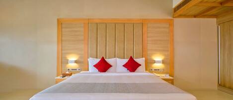 Une chambre d’hôtel avec un grand lit, une tête de lit en bois, des lampes de chevet et un coussin décoratif rouge.