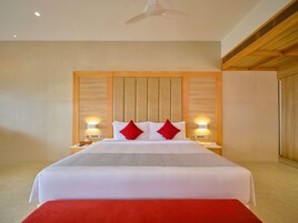 Een hotelkamer met een groot bed, een houten hoofdbord, bedlampjes en een rode sierkussen.