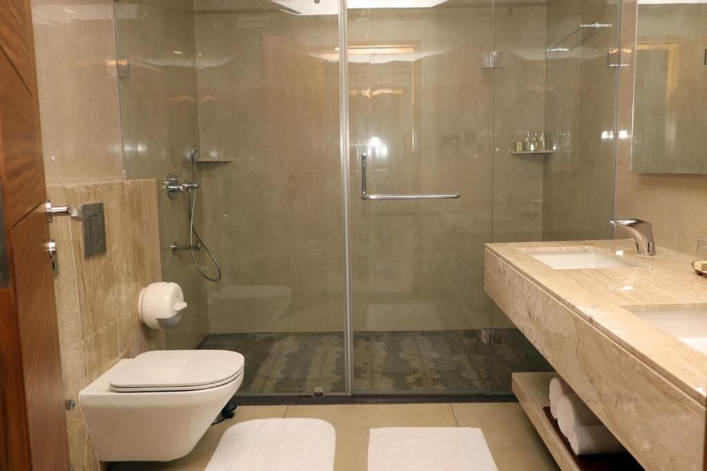 A modern bathroom with a glass-enclosed shower, a white toilet, and a marble vanity with a sink.