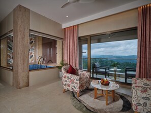 A modern living room with a large window, a sofa, a coffee table, and a view of the outdoors. - Vibe Munnar Resort & Spa (Devikolam)