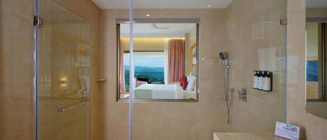 A hotel bathroom with a glass shower enclosure, a sink, and a mirror.