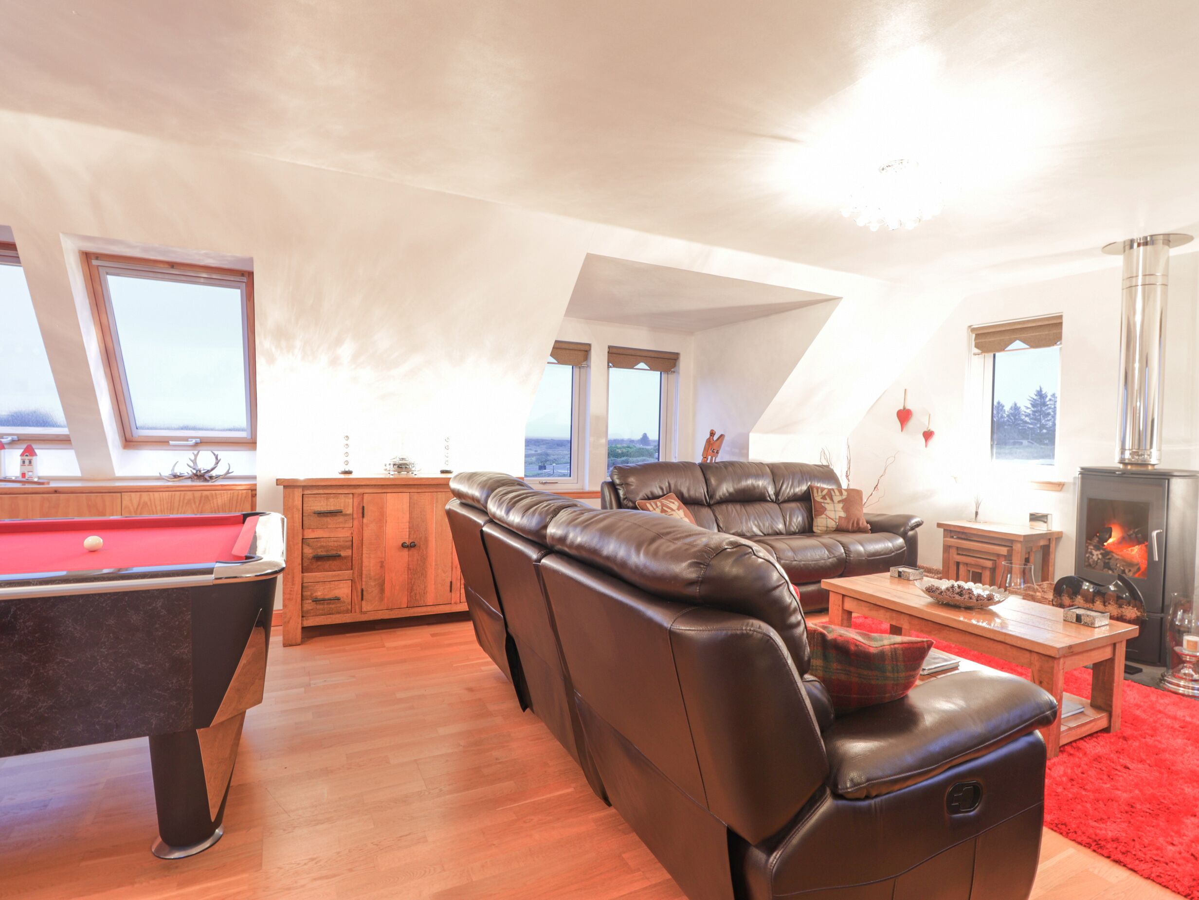 A cozy living room with a pool table, leather sofa, and a fireplace.