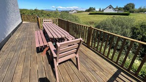 A wooden deck with a picnic table and benches, surrounded by a wooden railing. - Roselea (Strath)