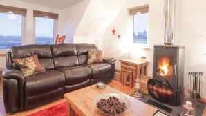 A cozy living room with a leather sofa, a wooden coffee table, and a wood-burning stove. - Roselea (Strath)
