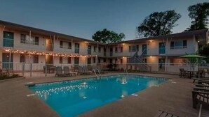 Un hotel con piscina, zona de estar al aire libre y un patio cubierto.
