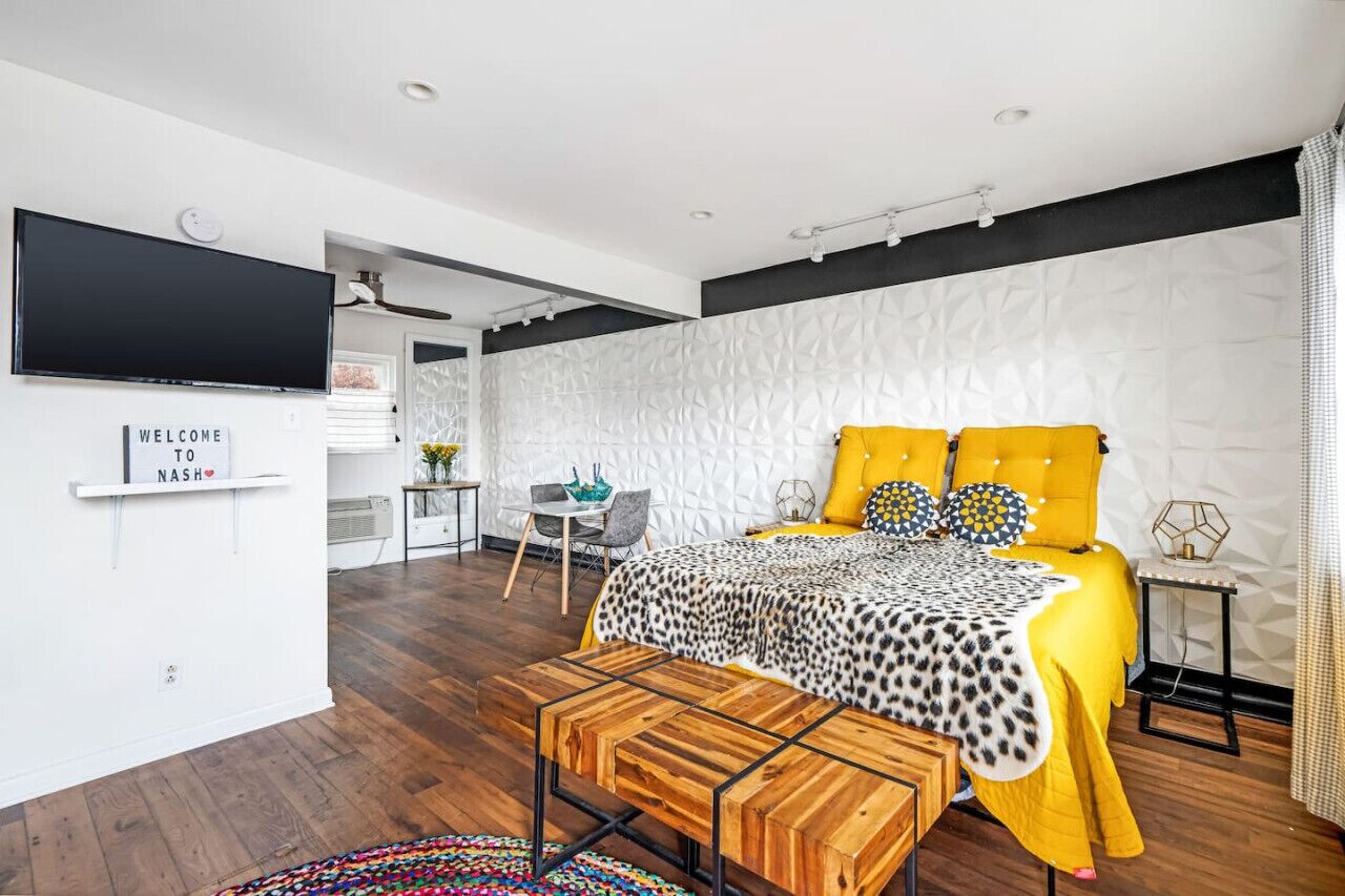A modern bedroom with a bed, a TV, a desk, and a chair.