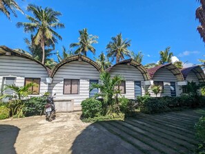 Fileira de edifícios brancos com telhados em arco, cercada por palmeiras e vegetação.