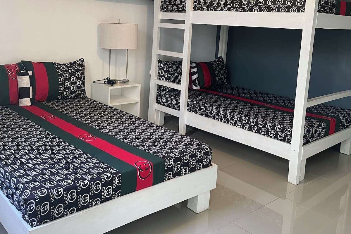 Una habitación con literas, una mesita de noche, una lámpara y una luz en el techo.