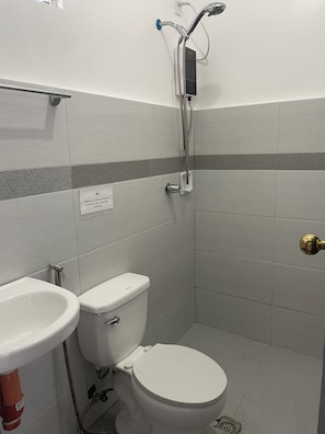 Un baño con inodoro, lavamanos y ducha.