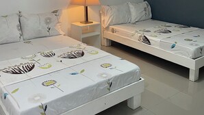 A room with two beds, a nightstand, a lamp, and a ceiling light. - Point F Siargao (General Luna)