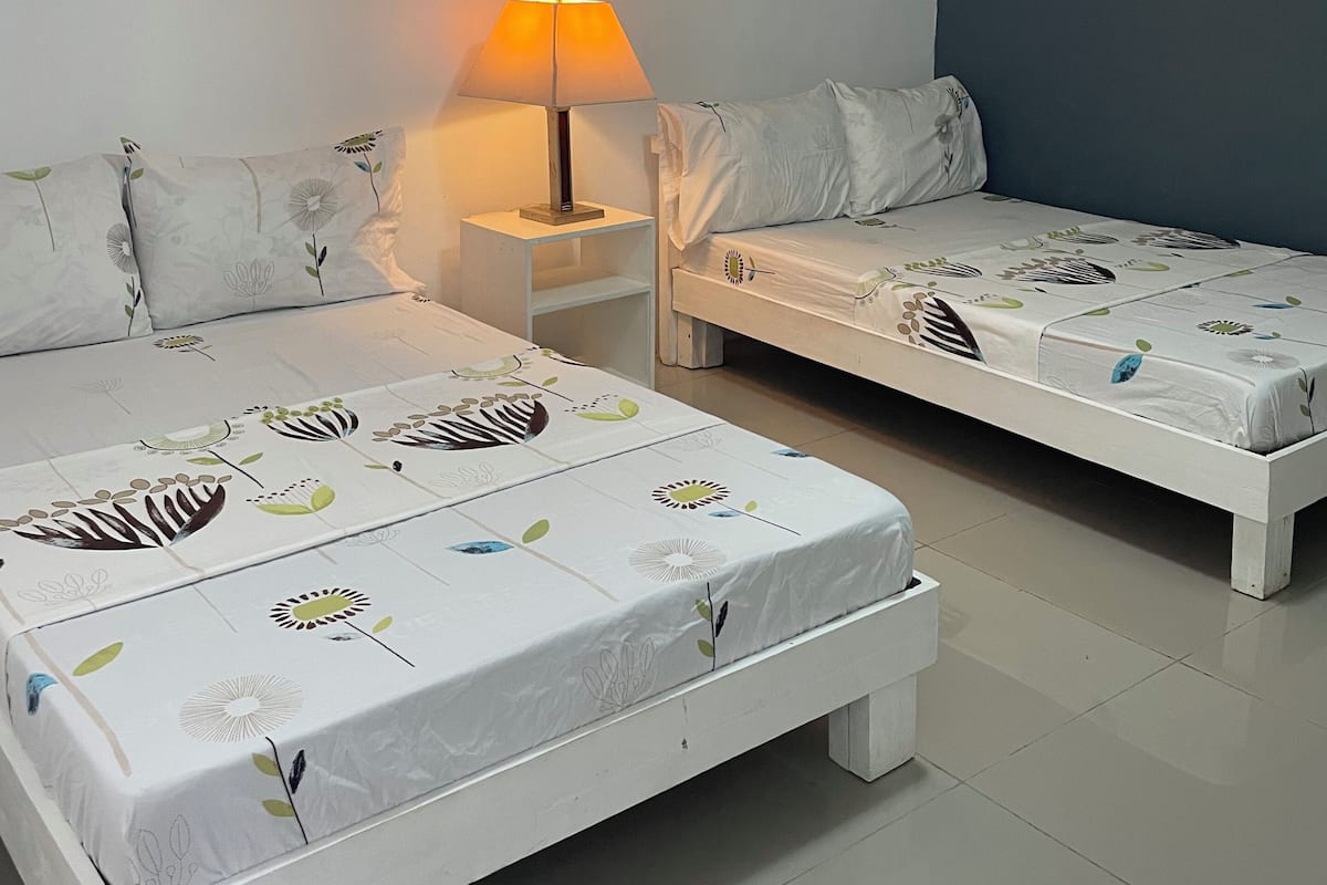 Una habitación con dos camas, una mesita de noche, una lámpara y una luz en el techo.
