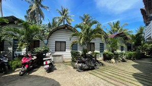 A courtyard with a building, palm trees, and parked motorcycles. - Point F Siargao (General Luna)