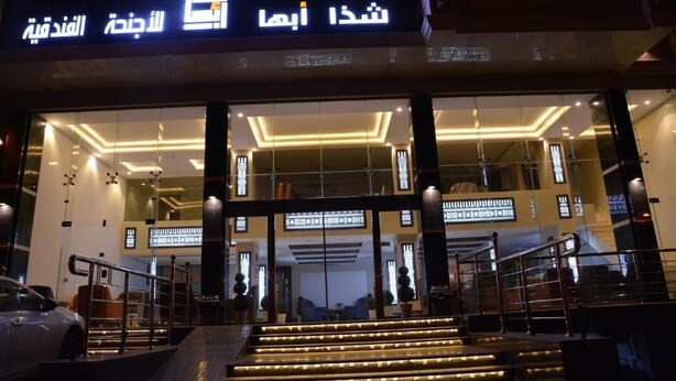 A hotel entrance with illuminated signage, a staircase, and a car parked outside. - Shatha Abha Furnished Units (Abha)