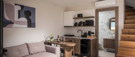Un espacio habitable compacto con sofá, mesa de comedor, zona de cocina y escalera.