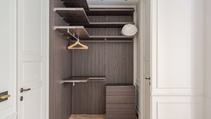 Un dressing avec des étagères en bois, une tringle à vêtements et un meuble de rangement.