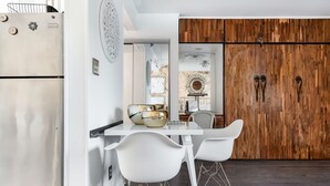 Une cuisine moderne avec des meubles blancs, un réfrigérateur en acier inoxydable et un coin repas comprenant des chaises et une table, le tout de couleur blanche.