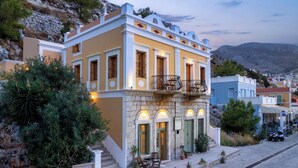 A two-story building with a balcony, stone steps, and potted plants. - 1st Floor Grey - Over The Sea Apartments with a sea view (Simi)