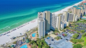 Un hotel frente al mar con vista a la playa, varios edificios altos y un estacionamiento.