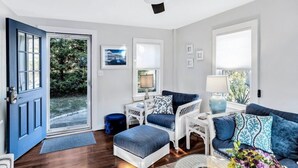 A living room with a blue door, white furniture, and a ceiling fan. - Falmouth Charm: Close to Main Street & Bike Trail RPAM098 (Falmouth)